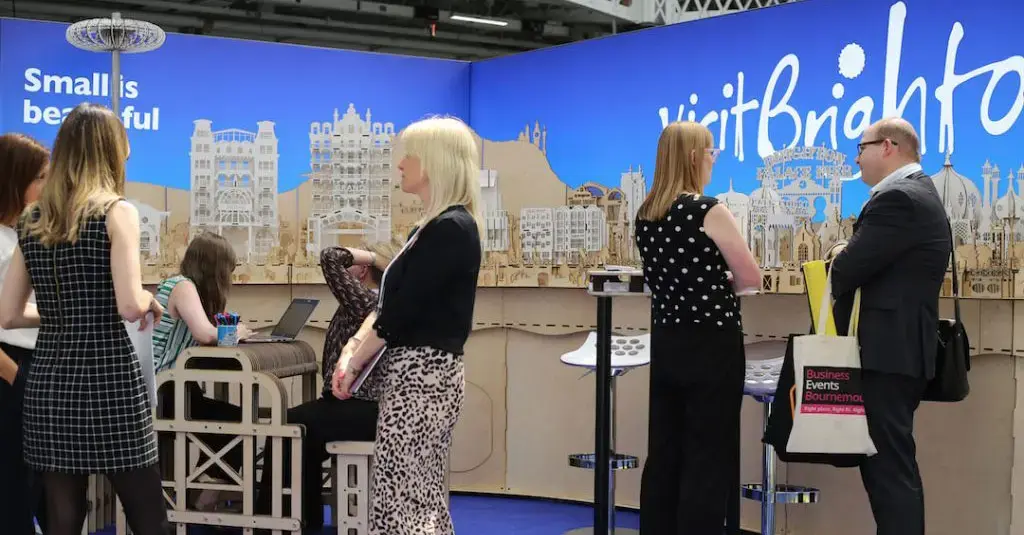 The Small is Beautiful VisitBrighton exhibition stand — a laser-cut miniature Brighton skyline — with visitors talking around it