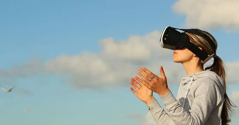 A woman wearing a VR headset against a blue sky, a bird in flight behind her